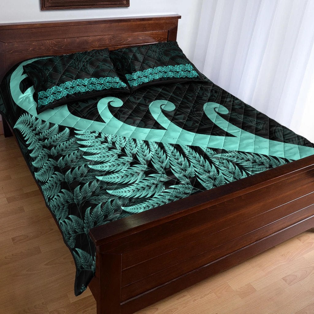 Dark quilt set with turquoise fern band and koru design on matching pillow