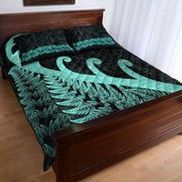 Dark quilt set with turquoise fern band and koru design on matching pillow