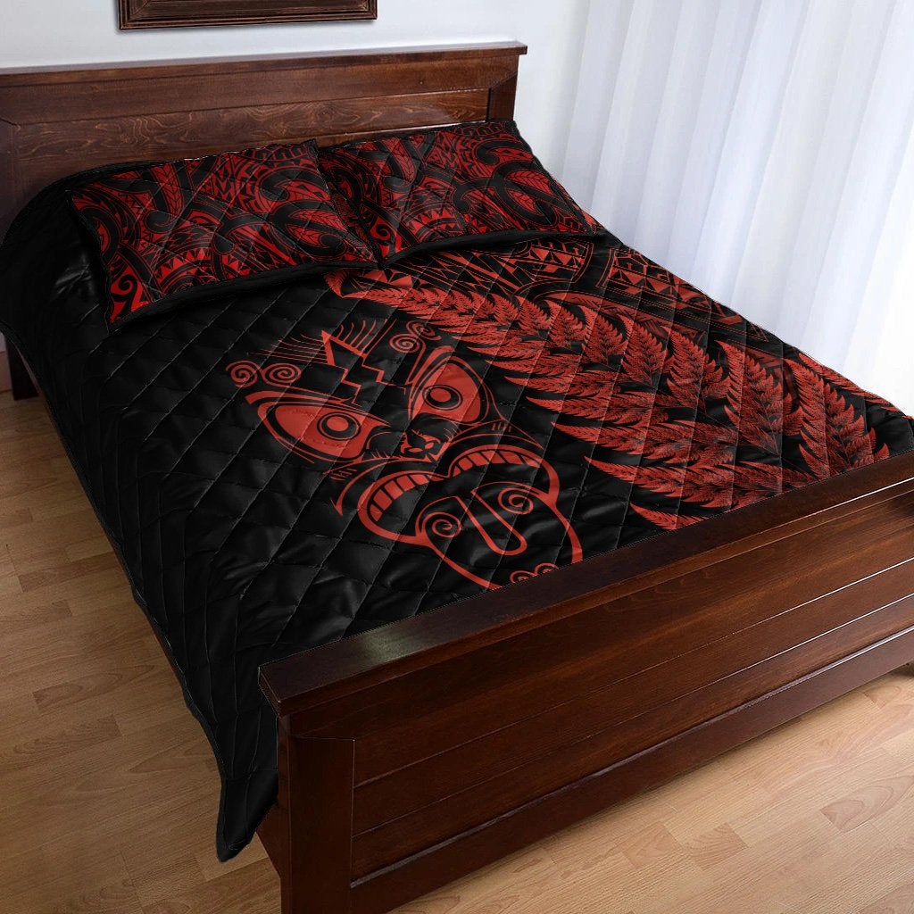 Black quilt with red Maori face and fern design, quilted bedding on bed