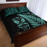 Turquoise-and-black quilt with woven tribal mask and fern design across the bedspread