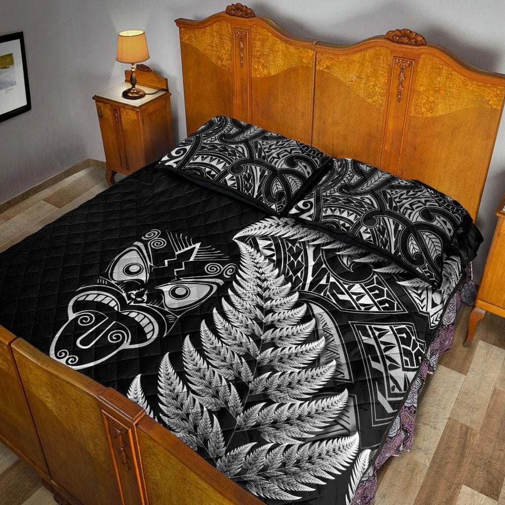 Black quilt bed set with silver fern design and Maori tribal patterns, with two pillows