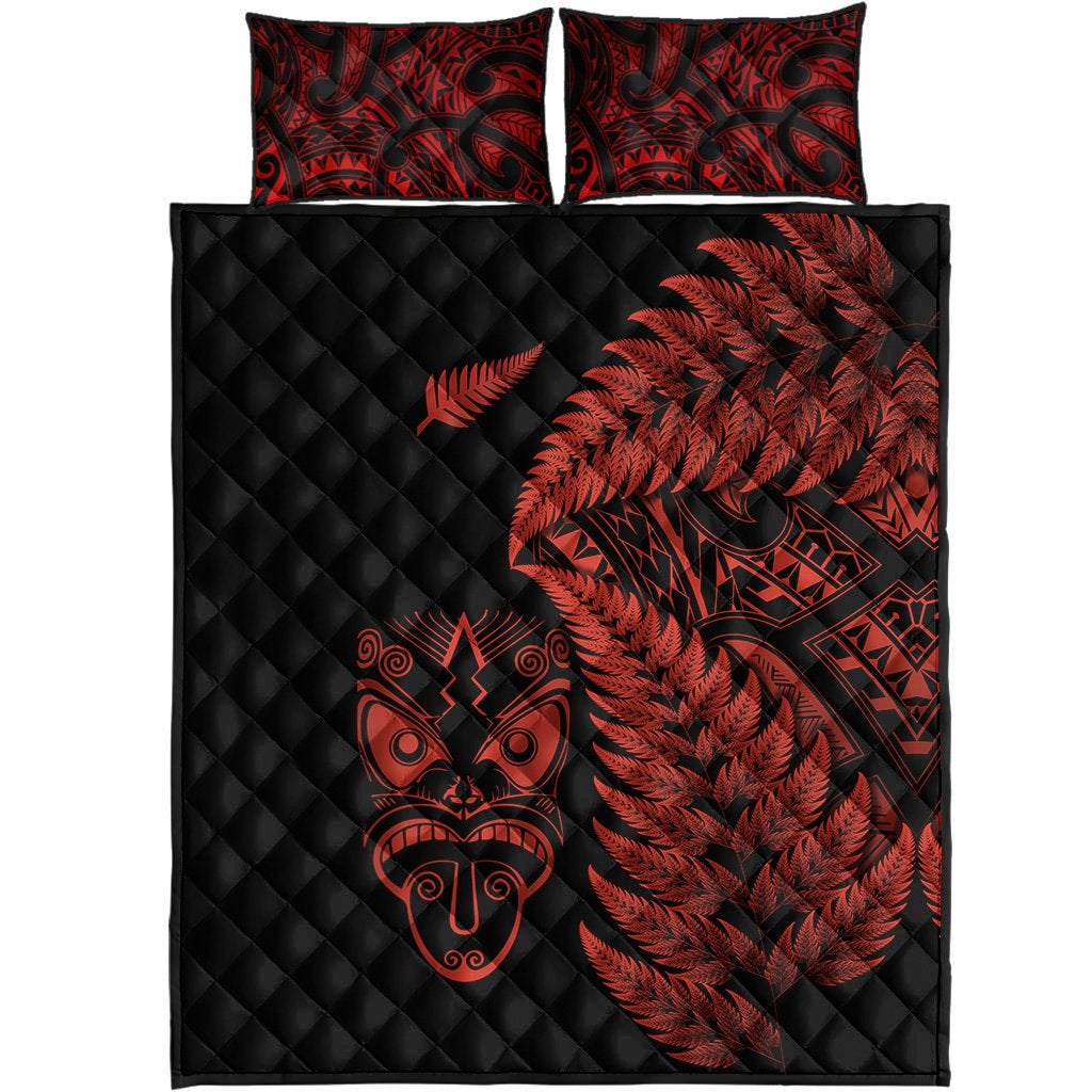 Black quilt with red fern and Maori face print, two matching square pillows