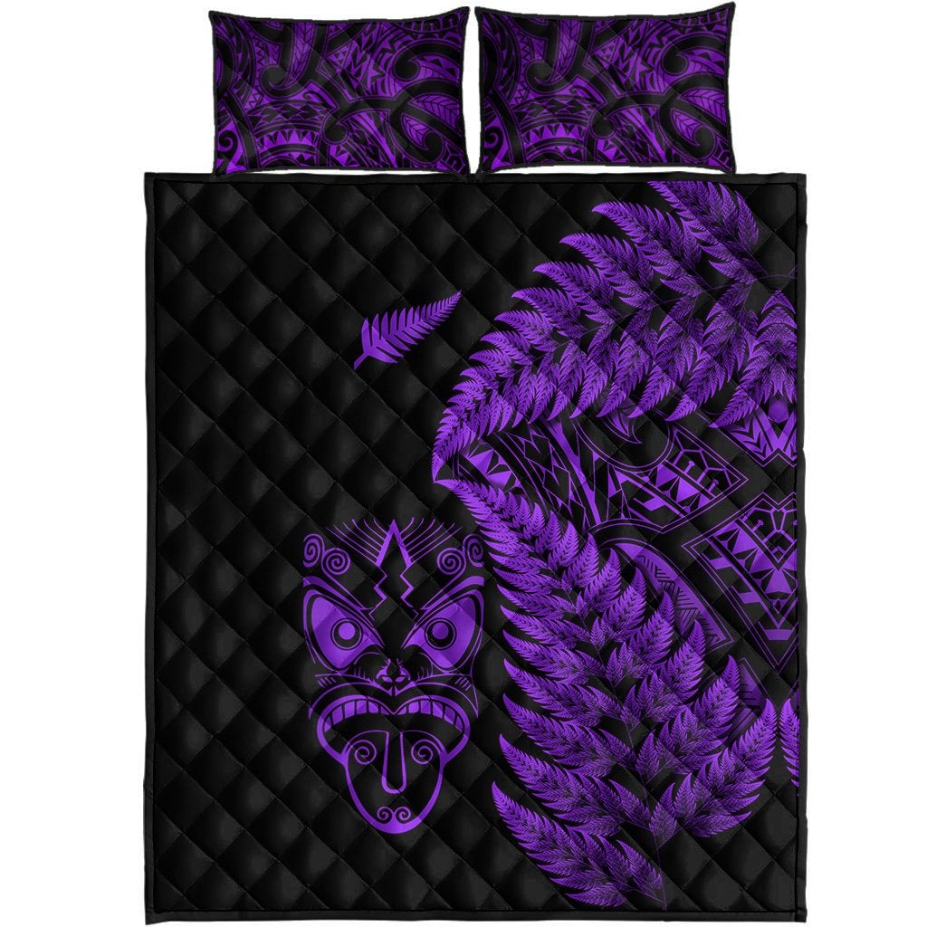 Front view: black quilt with purple fern and tribal face, two purple-pattern pillowcases