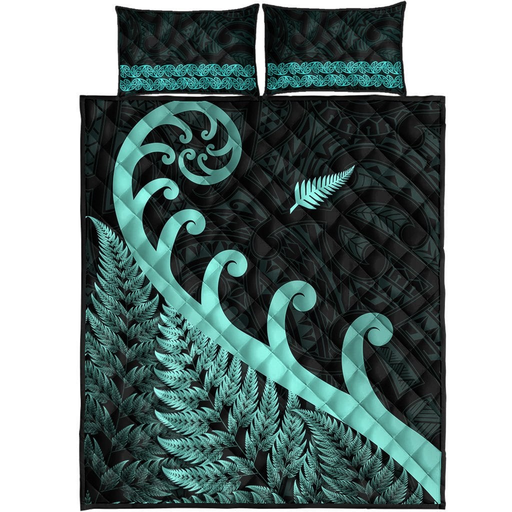 Folded view: dark and turquoise quilt set with fern print, koru swirl, and 2 pillows