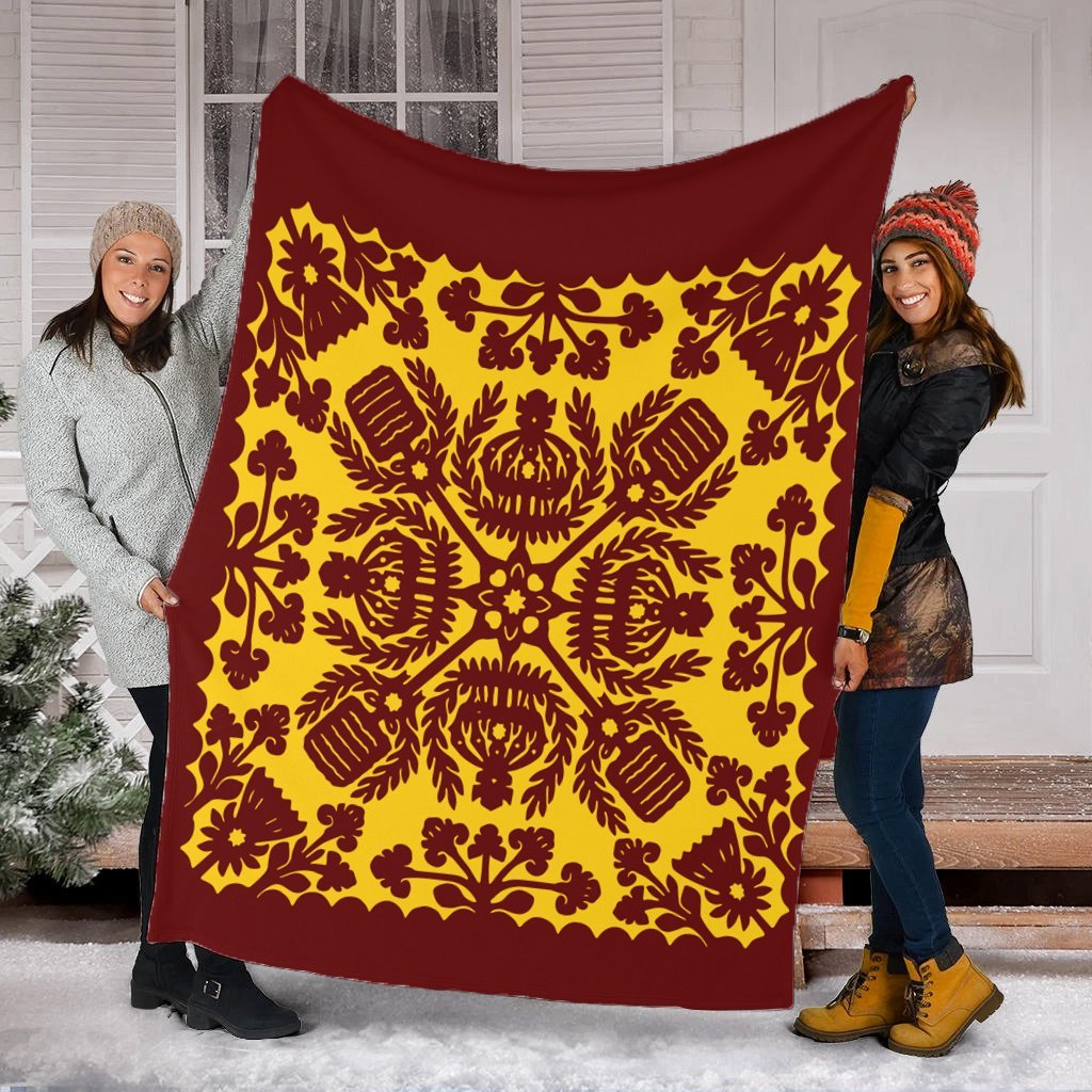 Red and yellow quilt-style blanket held up, ornate symmetrical pattern with scalloped edge