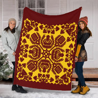 Red and yellow quilt-style blanket held up, ornate symmetrical pattern with scalloped edge