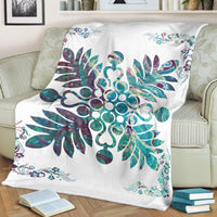 White blanket draped on sofa, showing teal hibiscus and tropical plant design