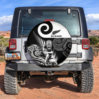 Circular black spare tire cover with white All Blacks logo and fern-spiral tribal pattern