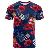Blue tropical T-shirt with red hibiscus, palms, and badge graphics; crew neck