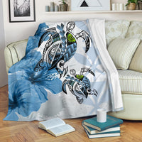 Blue Polynesian turtle and hibiscus premium blanket with tribal pattern, draped on couch