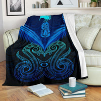Blue Maori manaia design blanket with teal tribal pattern, draped over a couch