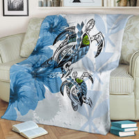 Blue Polynesian turtle and hibiscus blanket with tree-ray accents, draped over couch