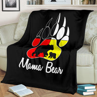 Black blanket draped on sofa featuring bear paw logo and 'Mama Bear' lettering