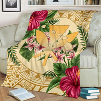 Gold Hawaiian blanket draped on sofa; hibiscus and plumeria flowers with palm leaf motifs