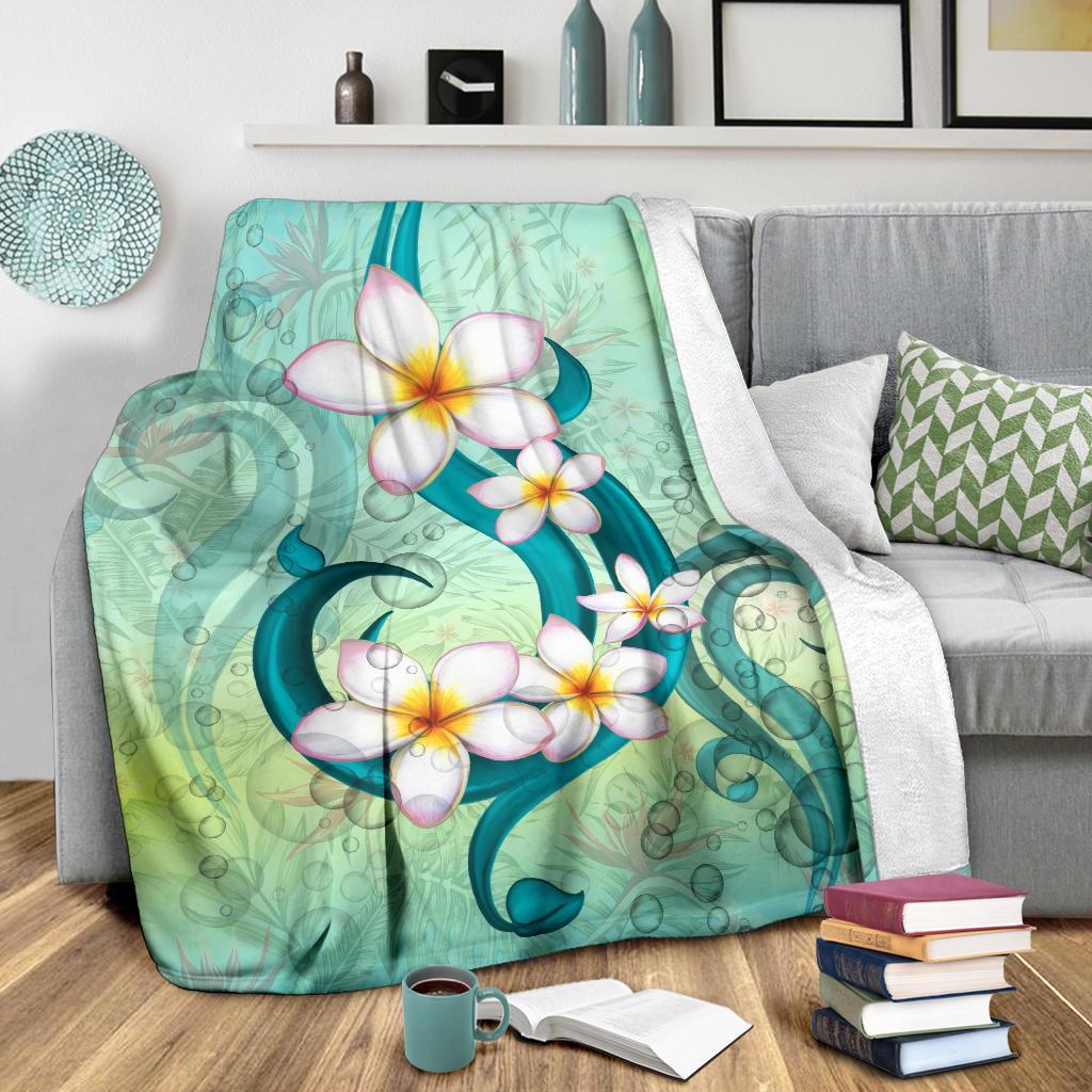 Hawaii plumeria premium blanket folded on bed, teal-green floral design with white flowers.