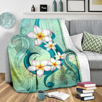 Hawaii plumeria premium blanket folded on bed, teal-green floral design with white flowers.