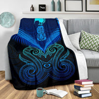 Blue Maori manaia blanket with teal tribal artwork, draped over a couch arm