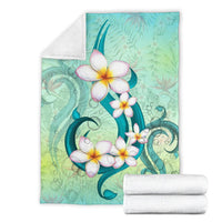 Hawaii plumeria blanket shown folded with a white backing; teal-green floral vine pattern.