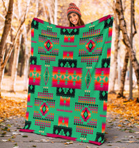Light green geometric blanket with tribal-inspired native pattern held up outdoors