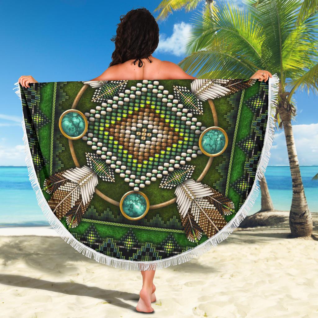 Green beach blanket draped outdoors, white fringe border around turquoise bead mandala