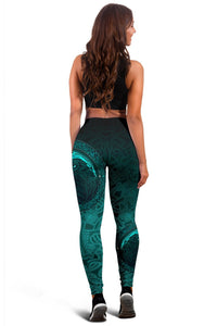 Back view black and teal leggings with raven face motif centered on thigh