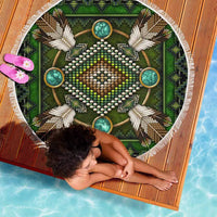 Green round beach blanket with central beaded face design, turquoise accents, white fringe