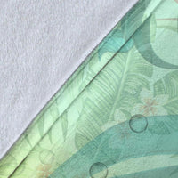 Close-up of Hawaii plumeria blanket fabric edge with teal-green leaf and bubble print.