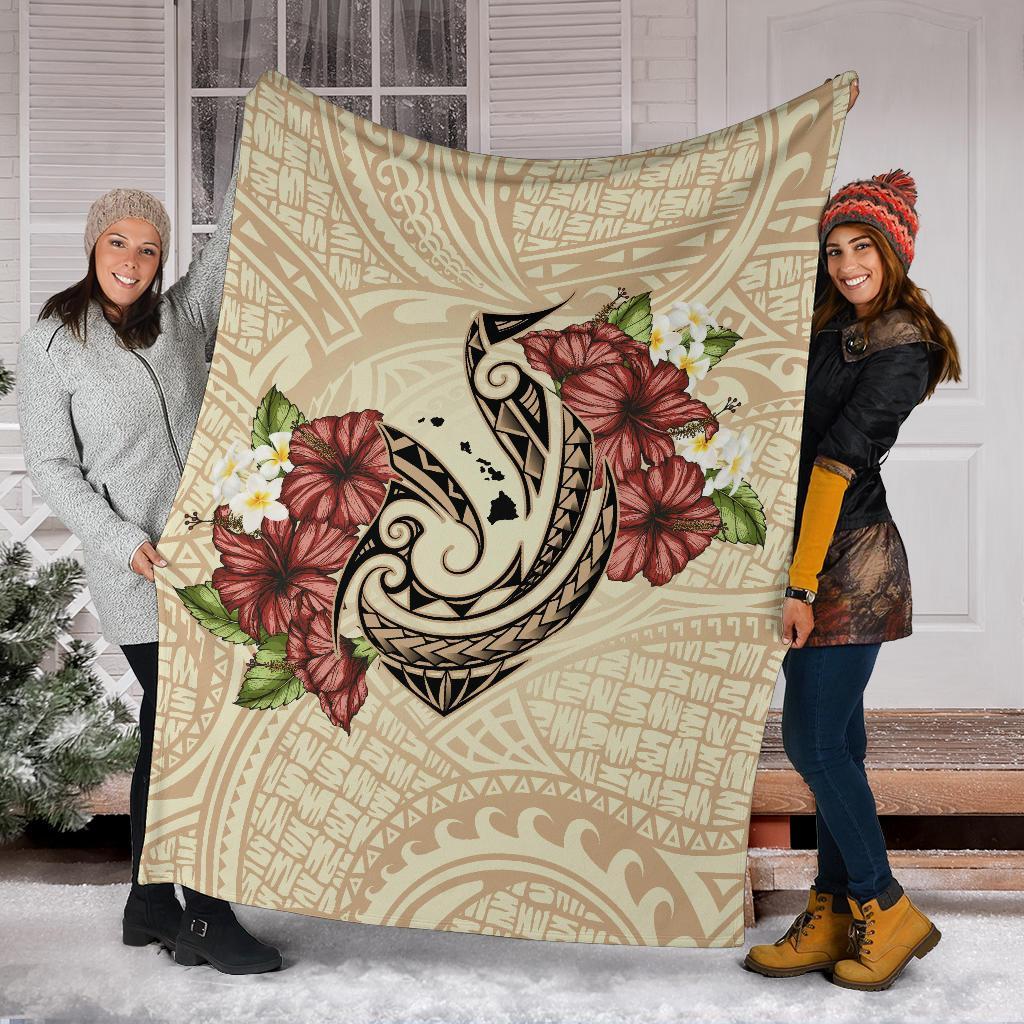 Beige Polynesian blanket displayed indoors, fish hook motif with hibiscus and plumeria print