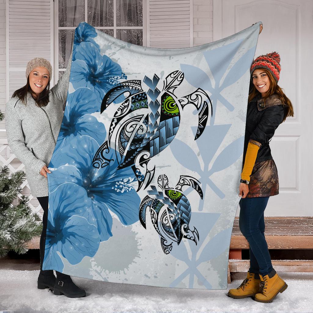 Blue Polynesian turtle and hibiscus blanket held up by two people, center turtle artwork
