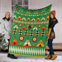 Green holiday blanket draped by two people; tents, bison, and dreamcatcher motifs