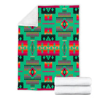 Light green geometric blanket with tribal pattern, folded and stacked with two rolled towels