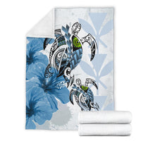 Blue Polynesian turtle and hibiscus blanket in studio, folded with roll-up blanket beside
