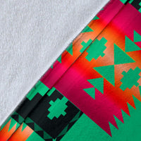 Close-up of light green blanket fabric with red, teal, and black geometric motif