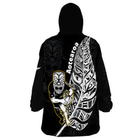 Black wearable blanket hoodie with hood and back print featuring Maori character graphic